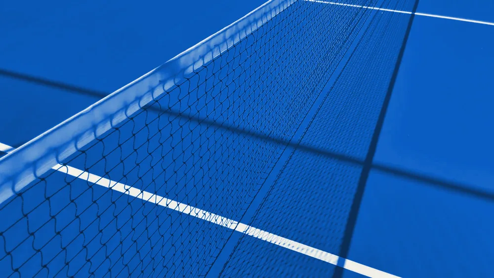 Close-up of a tennis net against a blue court